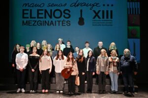 Grupė jaunų žmonių su muzikos instrumentais rankose ir festivalio organizatoriai stovi teatro scenoje 