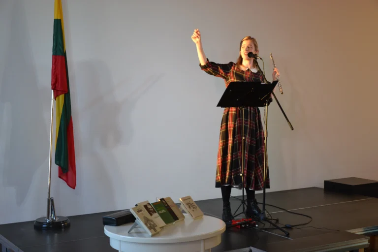 Poetinio-muzikinio pasirodymo metu aktorė Emilija Latėnaitė stovi prieš auditoriją